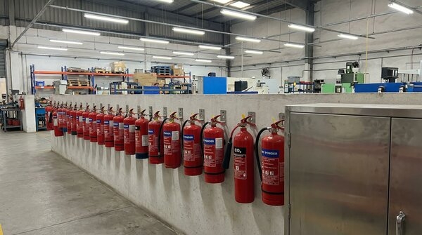 Row of portable fire extinguishers mounted on wall